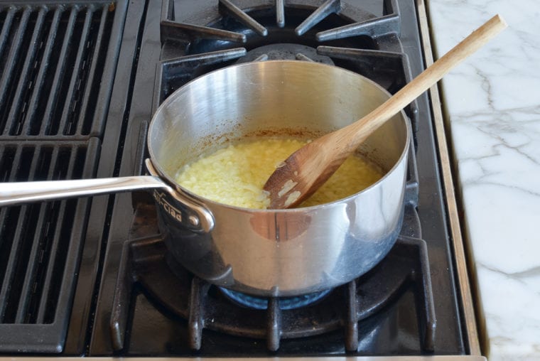 Wooden spoon in a pan with softened onions.