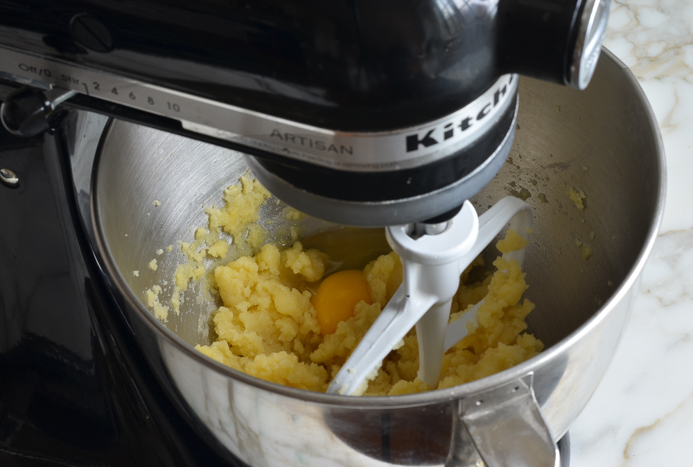 Egg and dough in the bowl of a stand mixer.