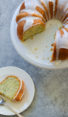Slice of lemon poppy seed cake next to the rest of the cake.
