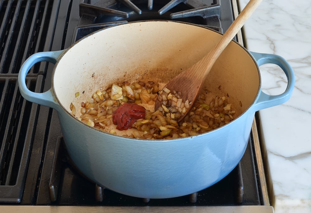 adding tomato paste to softened onions and garlic.