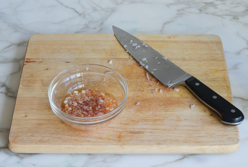 Knife next to a bowl of shallots and vinegar.
