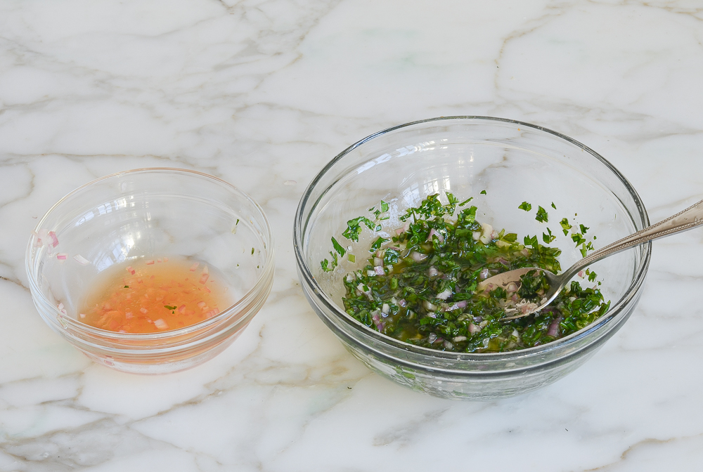 Small bowl of vinegar next to a bowl of herbs, shallots, and a little vinegar.
