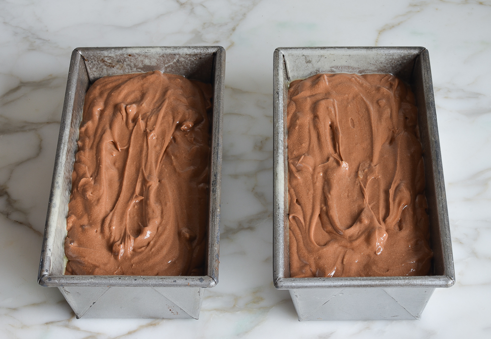 Two loaf pans filled with chocolate batter.