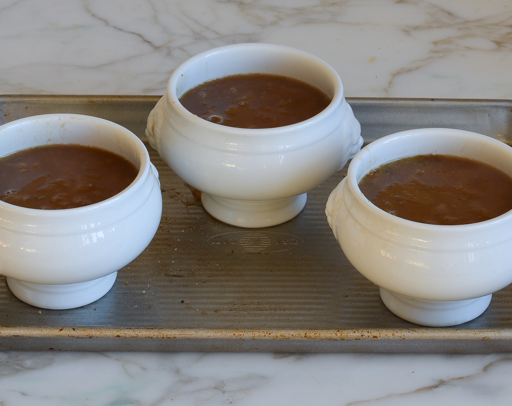 French onion soup crocks on baking sheet.