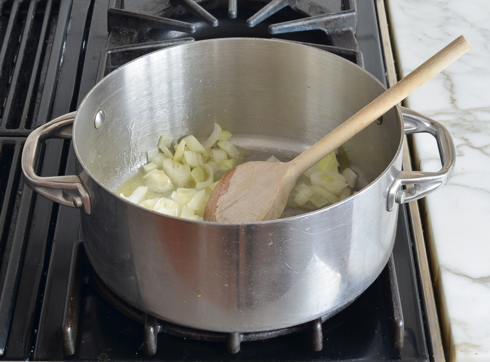 Onions cooking in a pan on a stovetop.