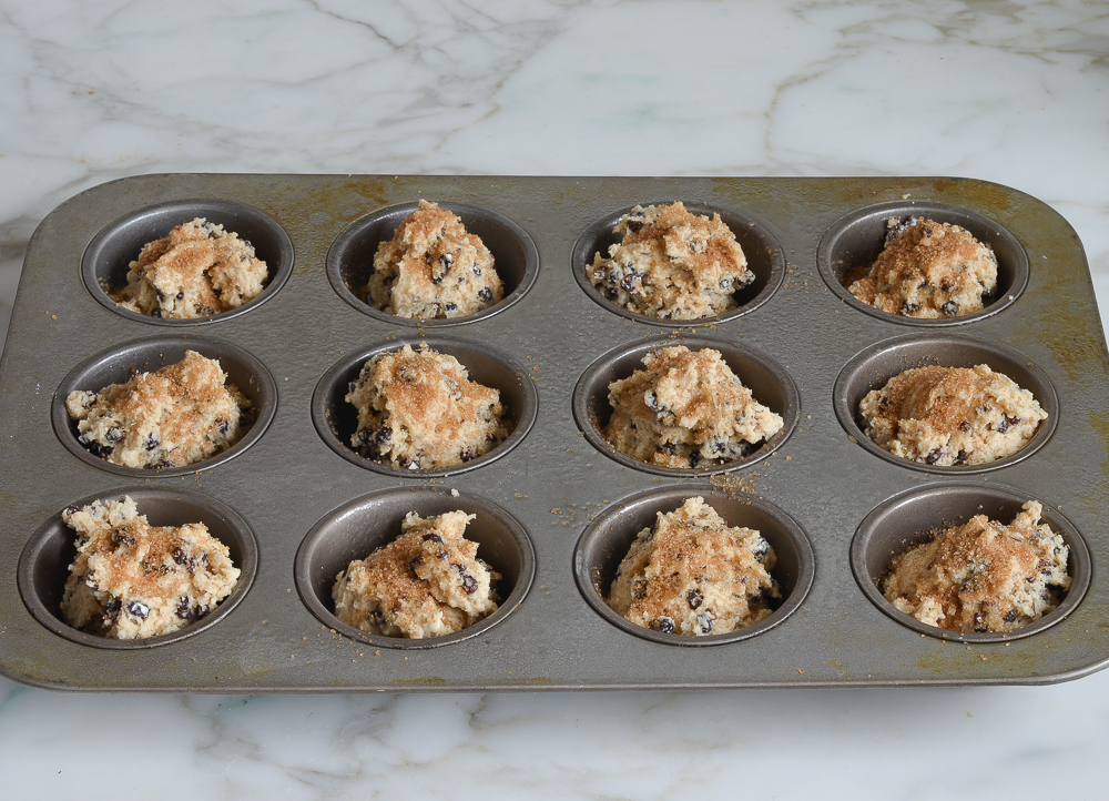 irish soda bread muffin batter scooped into muffin tin and sprinkled with coarse sugar