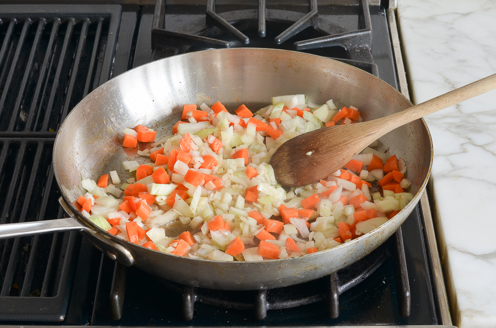 adding the onions and carrots to the skillet