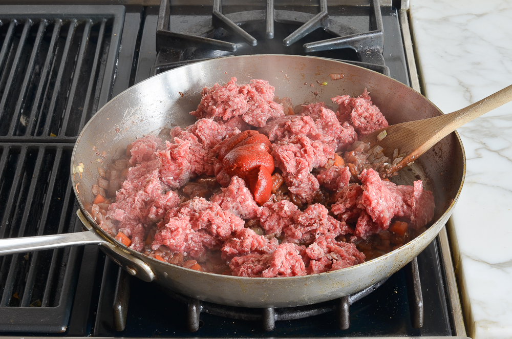 adding the beef and tomato paste to the skillet 