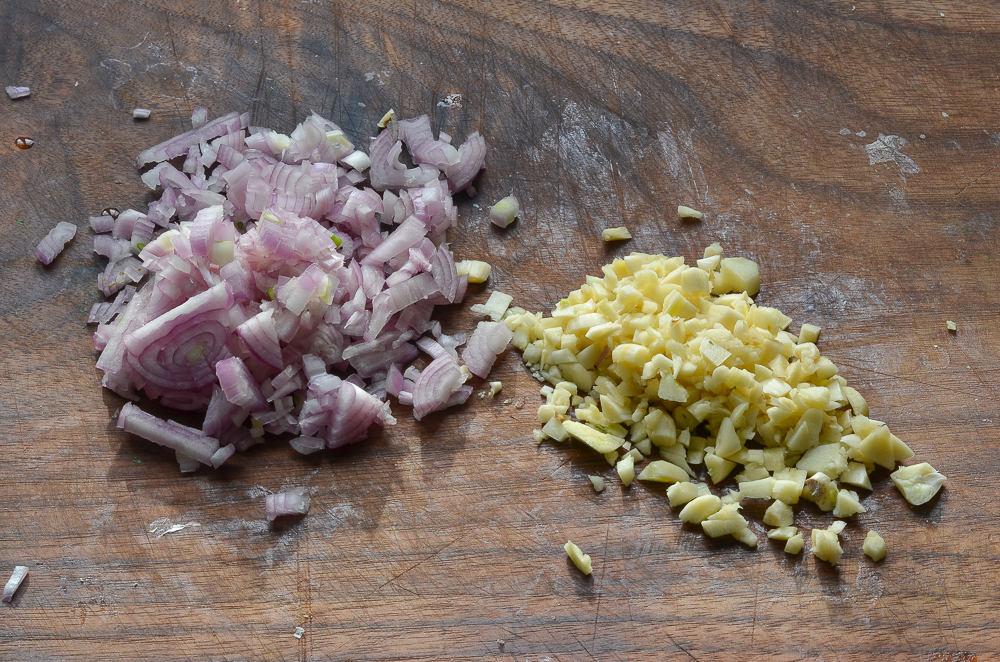 Red onions and garlic chopped on a cutting board.