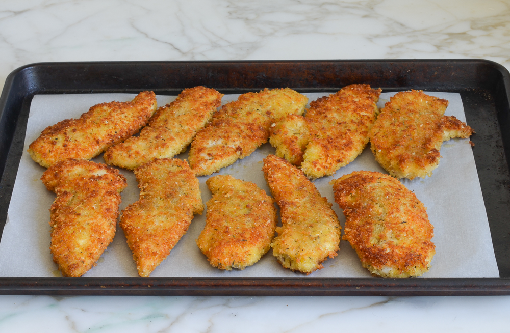 pan fried chicken arranged on lined sheet pan