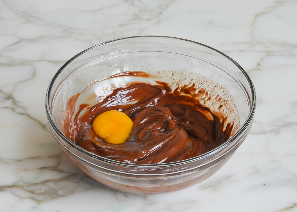 adding egg yolks one at a time to chocolate and butter mixture