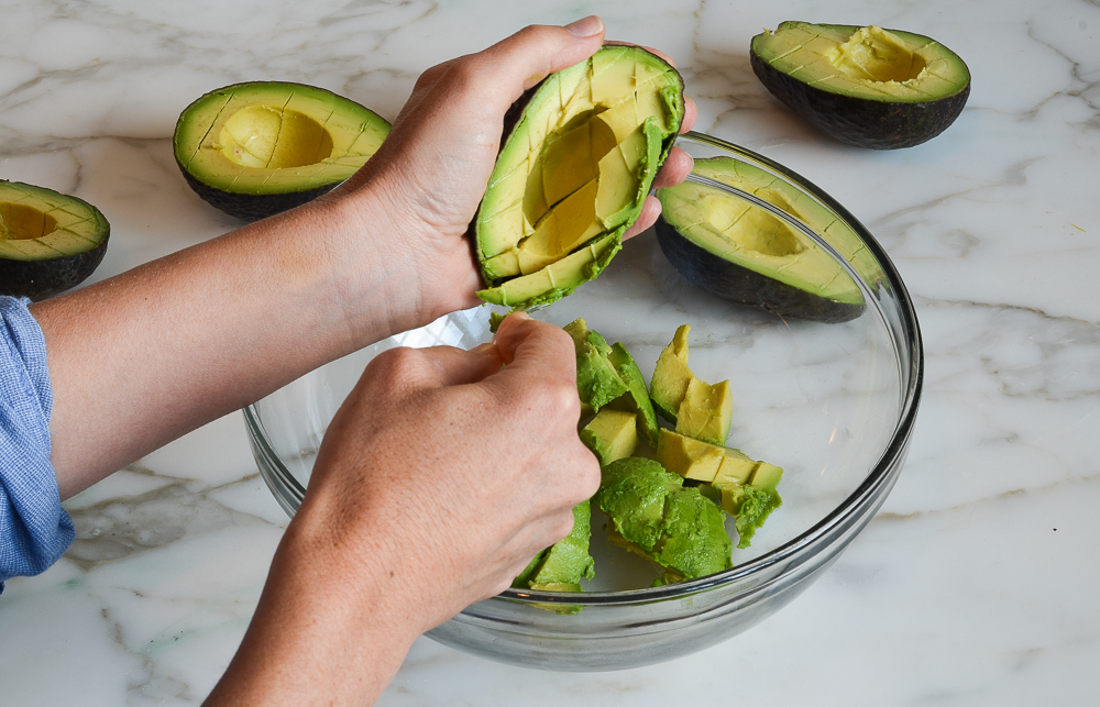 scooping the avocado flesh into the mixing bowl