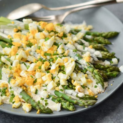 Plate of asparagus salad with hard-boiled eggs and creamy dijon dressing.