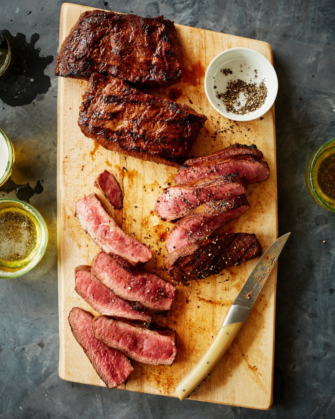 Sliced carne asada on a wooden cutting board.