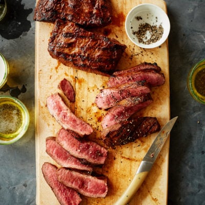 Sliced carne asada on a wooden cutting board.