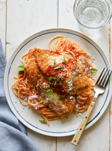 Chicken parmesan on a plate with a fork.