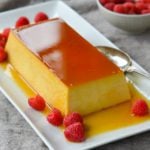 Best flan recipe served on a rectangle platter with raspberries.
