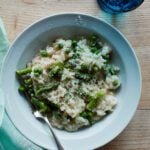Risotto recipe in bowl with Parmesan cheese and glass of sparkling water.