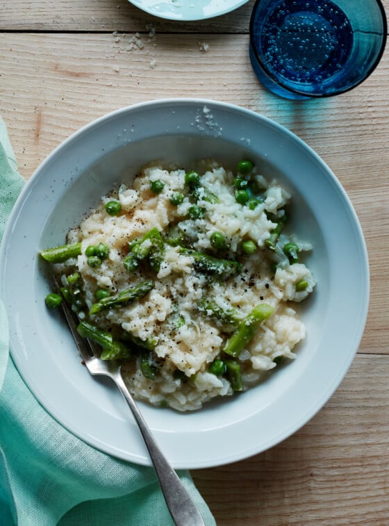 Risotto recipe in bowl with Parmesan cheese and glass of sparkling water.
