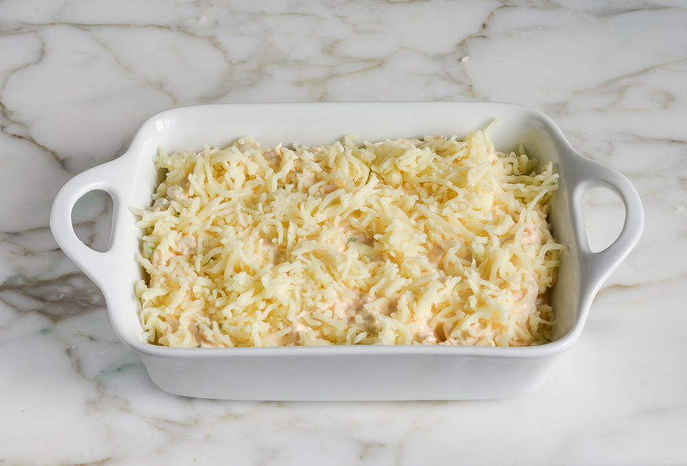crab rangoon dip topped with shredded cheese, ready to bake