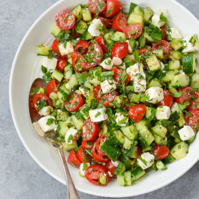 Spoon on a plate with Israeli salad with feta.
