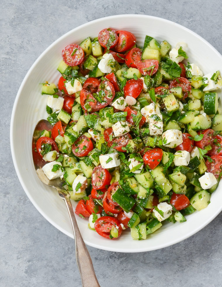 Spoon on a plate with Israeli salad with feta.