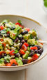 Spoon in a bowl of black bean salad with corn, avocado, and lime vinaigrette.