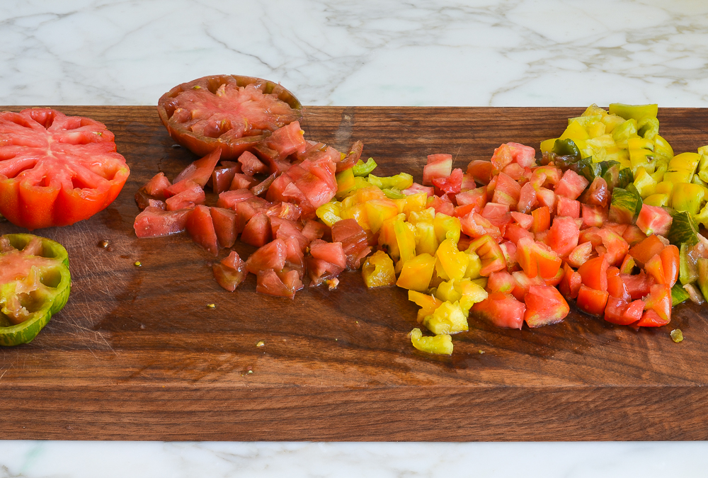 Different colors of chopped tomatoes on a cutting board.