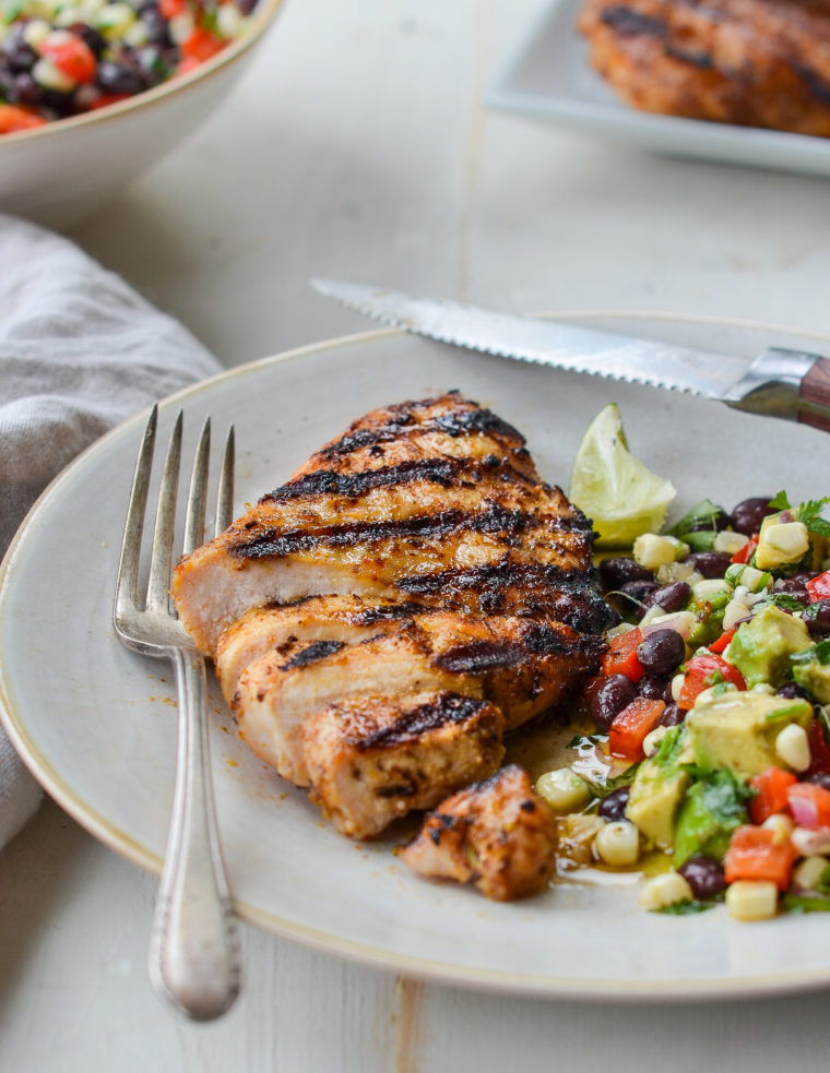 Grilled tequila lime chicken on a plate with a salad and a fork.