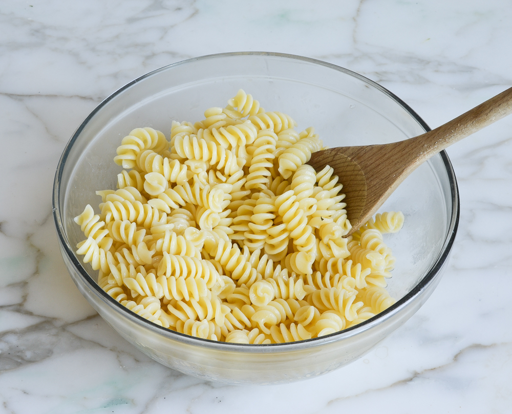 pasta tossed with olive oil in mixing bowl