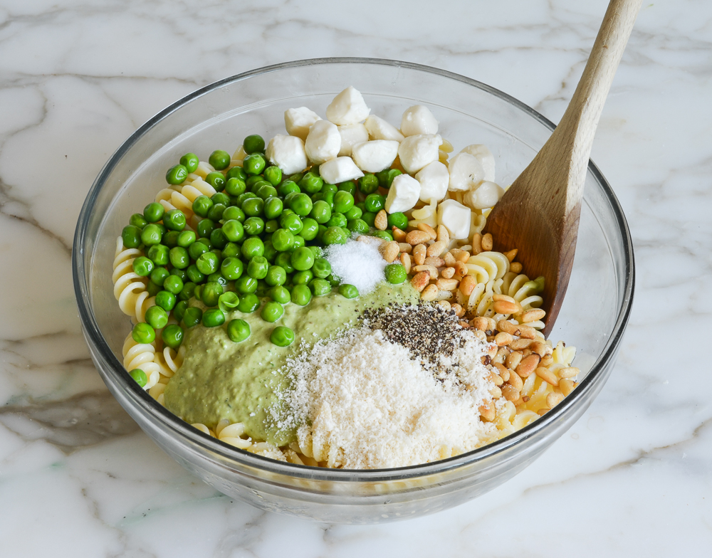 pasta, peas, cheese, and nuts in mixing bowl