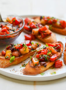 Plate of bruschetta with heirloom tomatoes, olives, and basil.