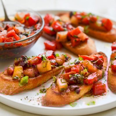 Plate of bruschetta with heirloom tomatoes, olives, and basil.