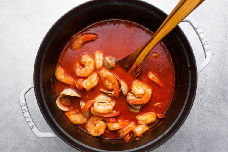 cioppino with opened clams and cooked shrimp