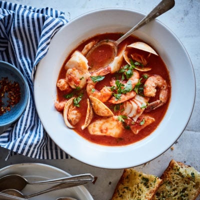 Bowl of cioppino with bread.