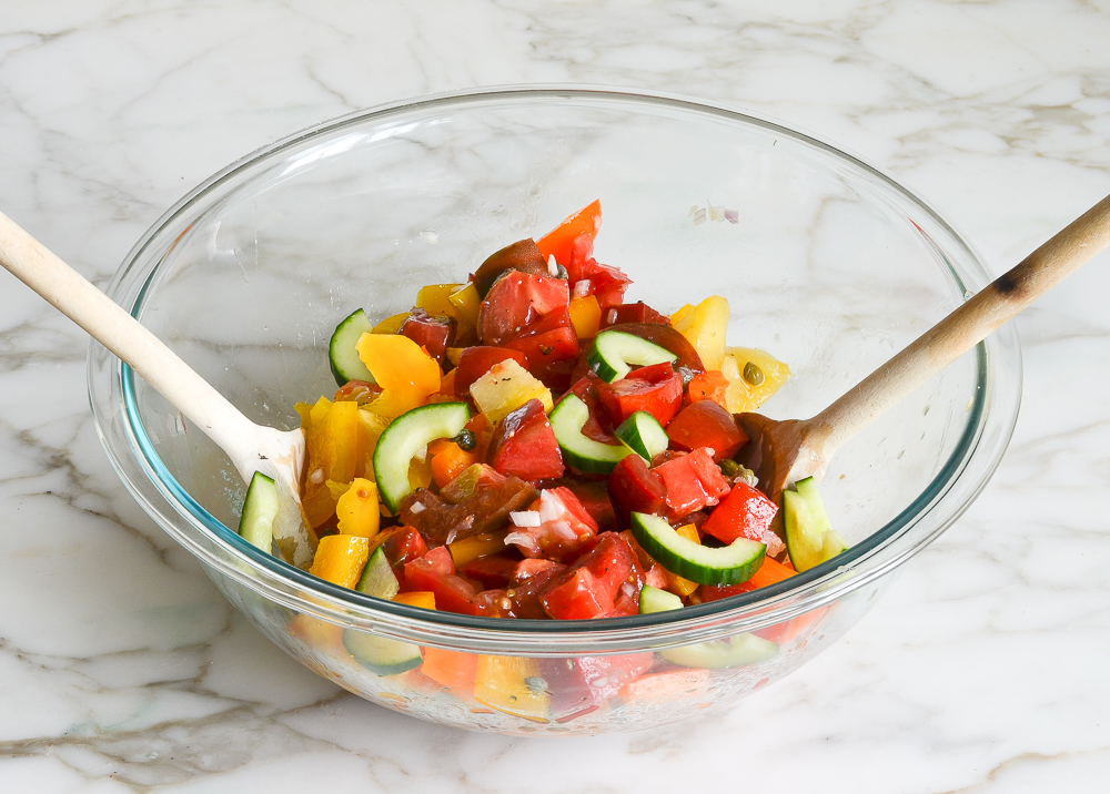 tossing vegetables with dressing for panzanella