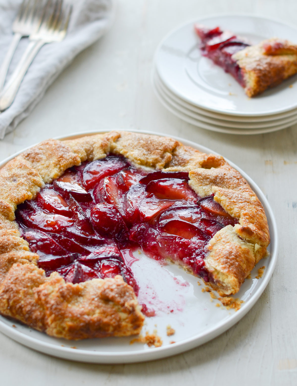 Plum galette on a plate missing a slice.