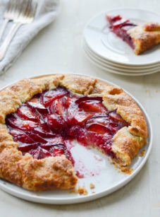 Plum galette on a plate missing a slice.