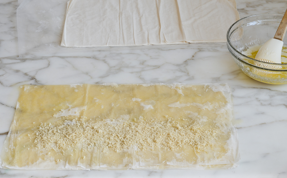 adding panko bread crumbs to stacked phyllo sheets