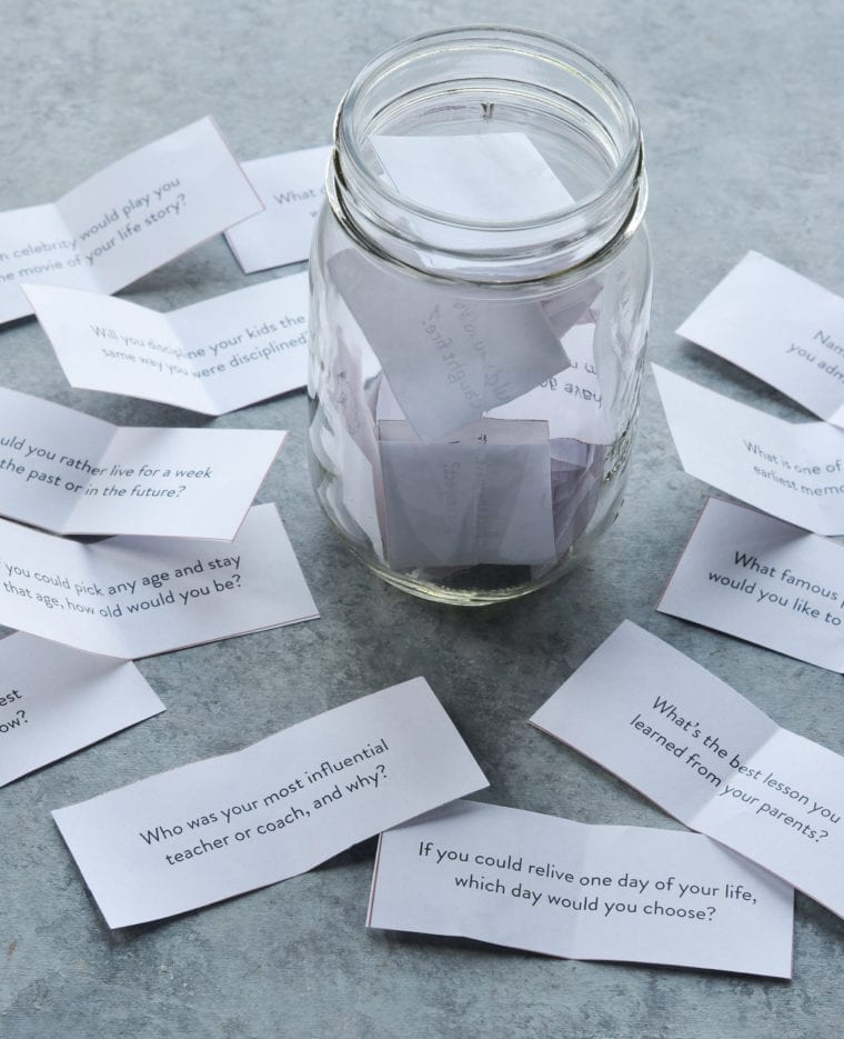 Jar surrounded by pieces of paper with questions written on them.