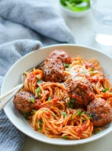 Fork on a plate with spaghetti and meatballs.