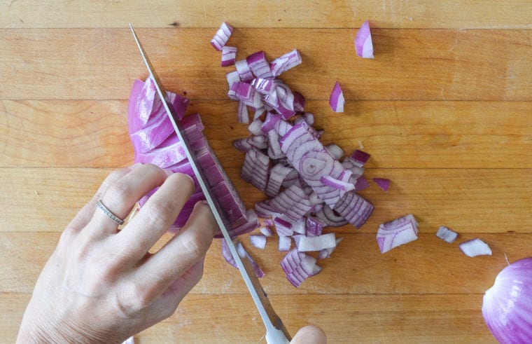 Person cutting an onion lying on its side.