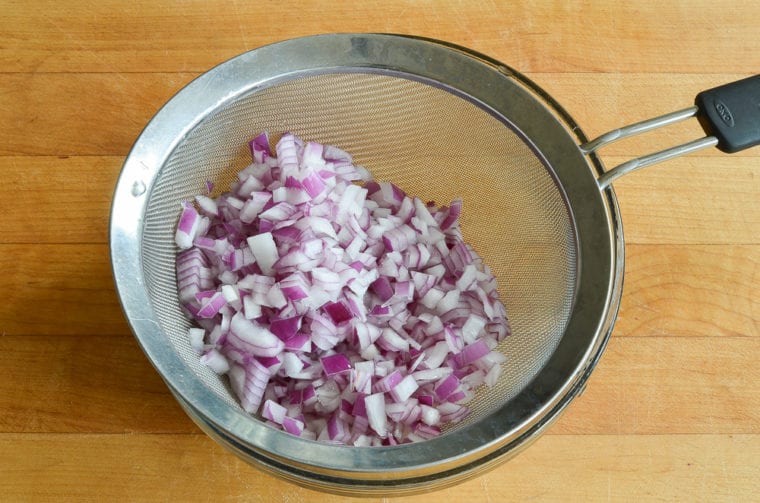 Diced red onion in a sieve.