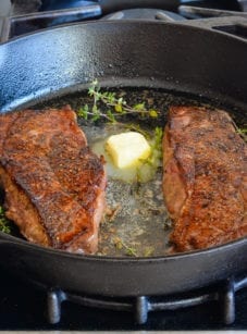 Steak in a skillet with butter.