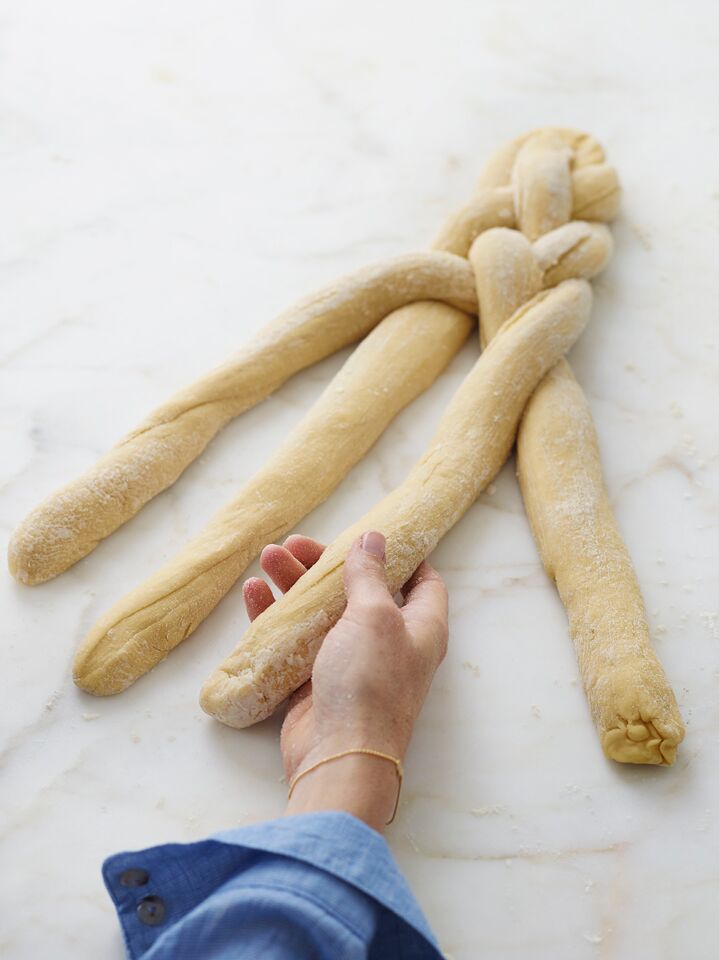 Person grabbing the third out of four strands of challah dough.