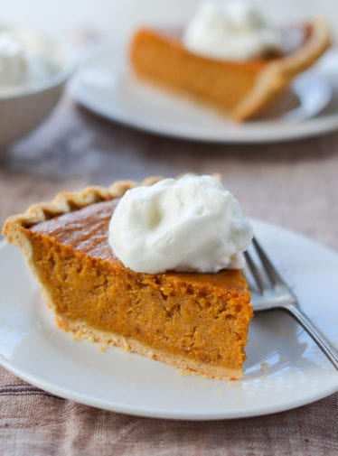 Slice of sweet potato pie on a plate with a fork.