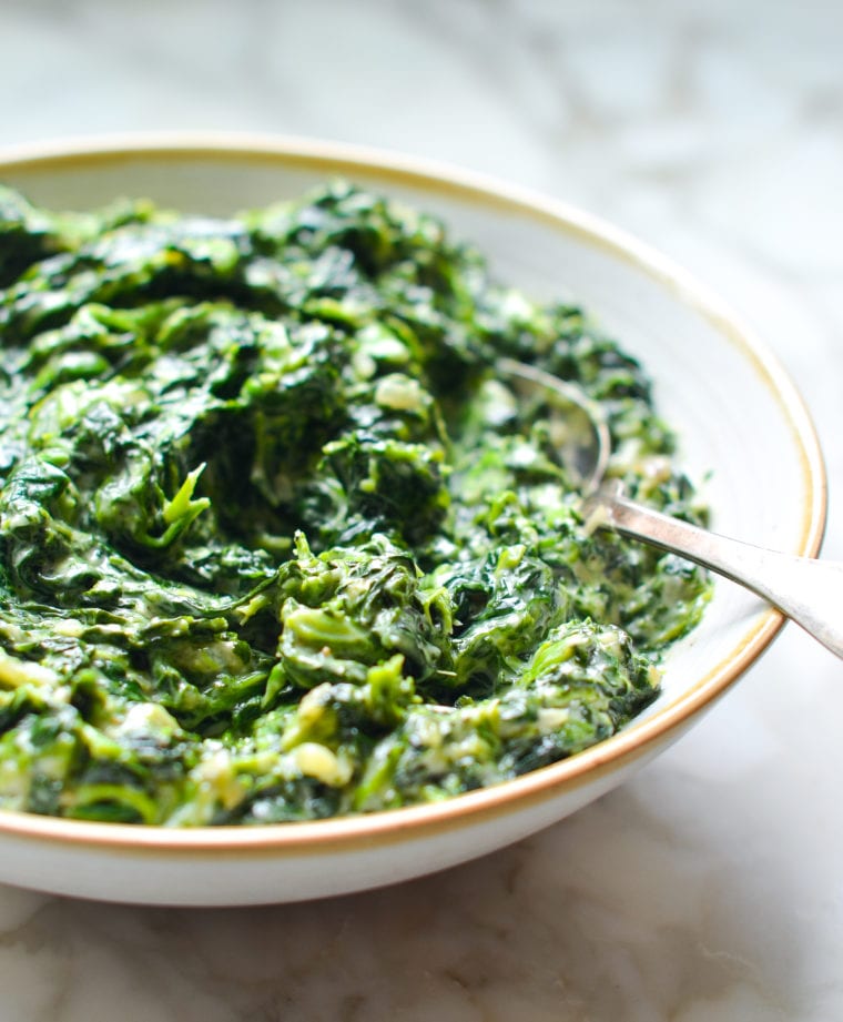 Spoon in a bowl of creamed spinach.