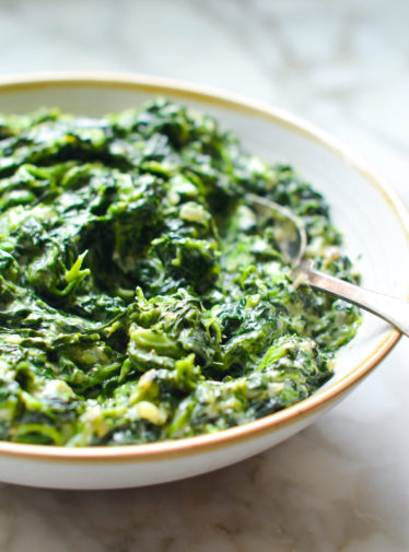 Spoon in a bowl of creamed spinach.