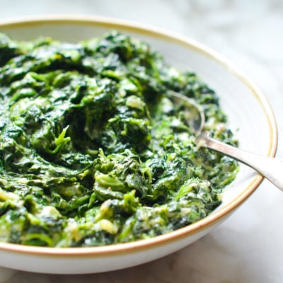 Spoon in a bowl of creamed spinach.