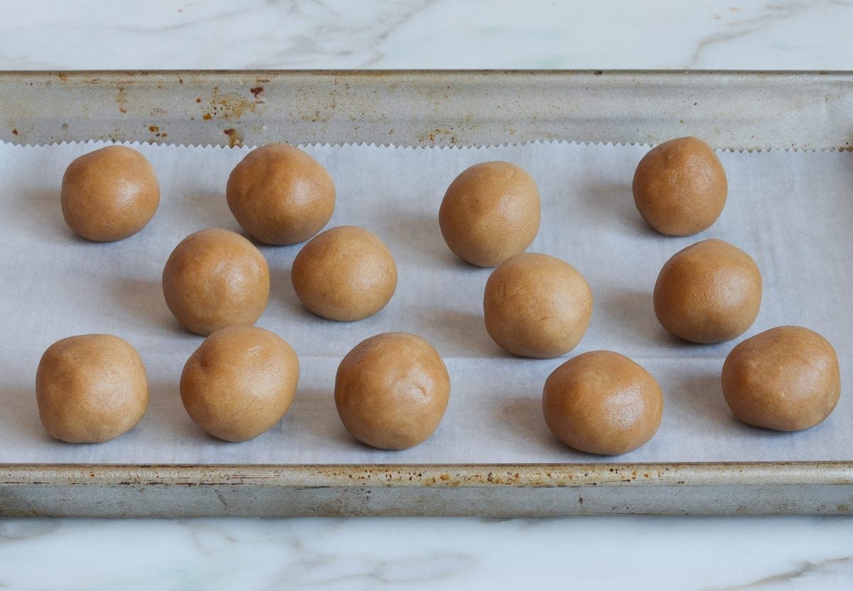 Dough balls on a lined baking sheet.
